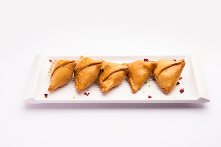 Indian sweet samosa is a Fried pastry soaked in sugar syrup filled with coconut, nuts and fruitsの素材