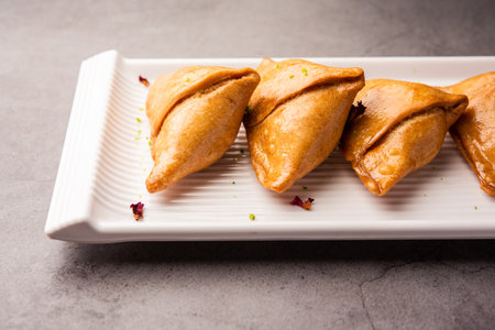 Indian sweet samosa is a Fried pastry soaked in sugar syrup filled with coconut, nuts and fruitsの写真素材