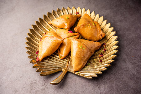 Indian sweet samosa is a Fried pastry soaked in sugar syrup filled with coconut, nuts and fruits