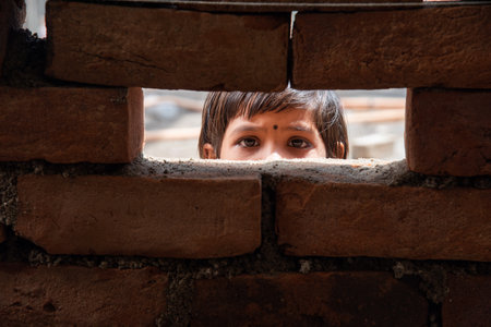 An Indian labour girl child looking  through under construction brick wall windowの写真素材