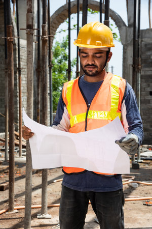 Indian man or asian construction worker holding roll paper of drawing Structural plan at site