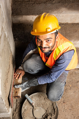 Happy Indian male construction worker constructing brick wall - hard working concept, manual labourの写真素材