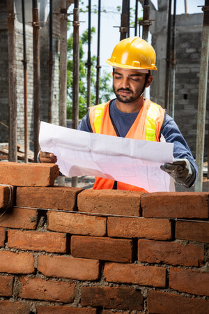 Indian man or asian construction worker holding roll paper of drawing Structural plan at siteの写真素材