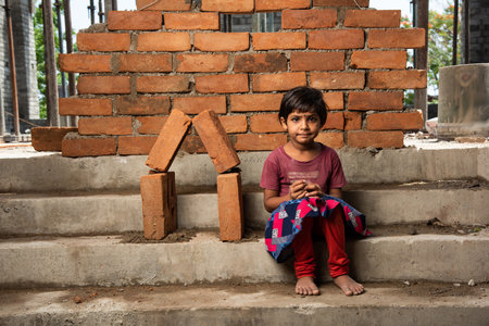 Indian asian Labour girl child posing besides conceptual brick house at construction siteの写真素材