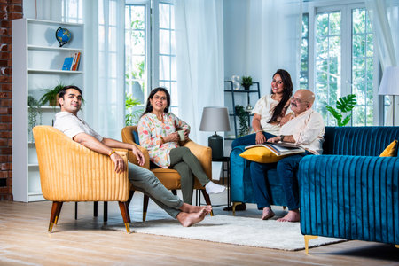 Indian family of four posing for a group photo in living room at modern homeの写真素材