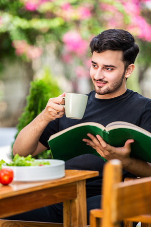 Indian man reading book outdoorsの写真素材