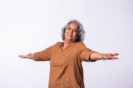 Exuberant senior asian indian woman with arms outstretched or spread on white backgroundの写真素材