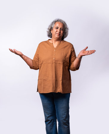 Exuberant senior asian indian woman with arms outstretched or spread on white backgroundの写真素材