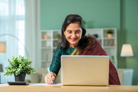 Senior Indian asian woman using laptop and papers for accounting at homeの写真素材