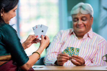 Senior Indian asian couple enjoying playing cards together at homeの写真素材