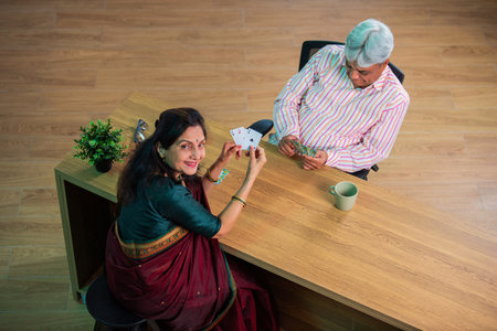 Senior Indian asian couple enjoying playing cards together at homeの写真素材