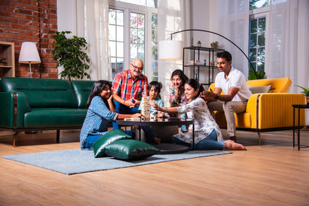 Indian asian multigenerational family playes wooden block stacking game at home together and having funの写真素材