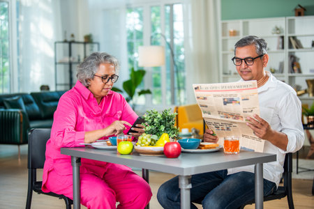 A happy mature Indian asian senior couple having breakfast together at home.の写真素材