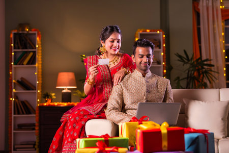 Indian asian couple in traditional wear online shopping on laptop on diwali or festival eveningの写真素材
