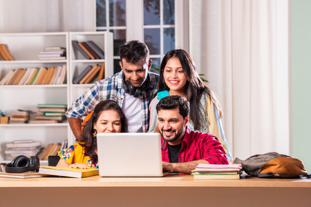 Indian asian four college or university students using laptop for study at tableの写真素材