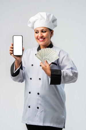 Young Indian asian female chef with smartphone and money fan - professional cookの写真素材