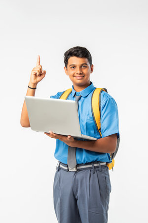Indian Asian school boy in uniform giving thumbs up, presenting or celebrating success, isolatedの写真素材