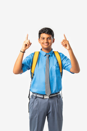 Indian Asian school boy in uniform giving thumbs up, presenting or celebrating success, isolatedの写真素材