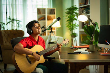 Indian Asian boy learning guitar online, recording a video, and pursuing a hobby at homeの写真素材