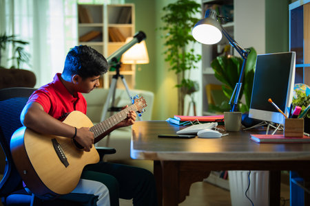 Indian Asian boy learning guitar online, recording a video, and pursuing a hobby at homeの写真素材