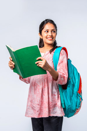 Indian asian young college girl with backpack, laptop, books pointing or ok signの写真素材