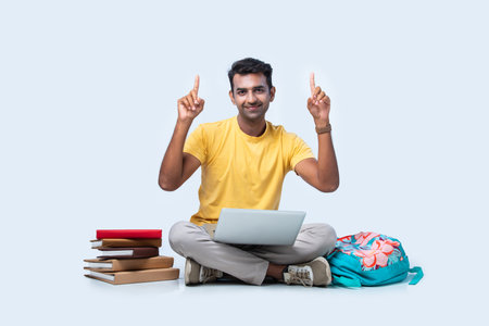 Indian asian male college student studying while sitting isolated on white backgroundの写真素材
