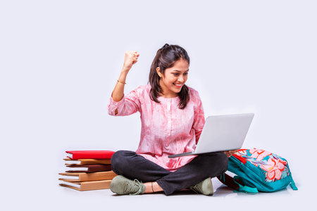 Indian asian female college student studying while sitting on white background with laptop booksの写真素材