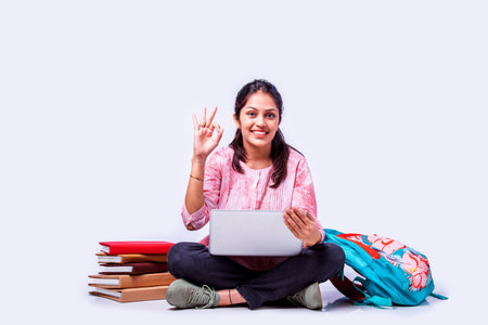 Indian asian female college student studying while sitting on white background with laptop booksの写真素材