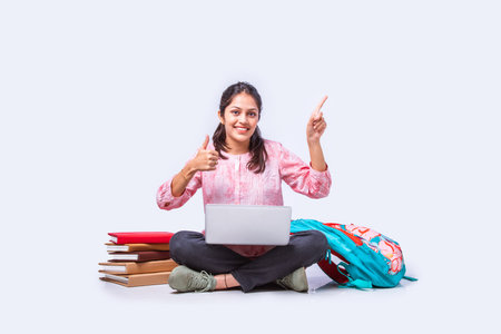 Indian asian female college student studying while sitting on white background with laptop booksの写真素材
