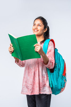 Indian asian young college girl with backpack, laptop, books pointing or ok signの写真素材