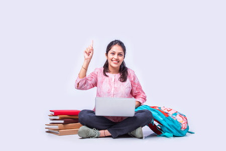 Indian asian female college student studying while sitting on white background with laptop booksの写真素材