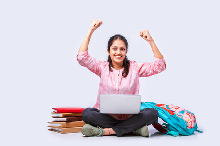 Indian asian female college student studying while sitting on white background with laptop booksの写真素材