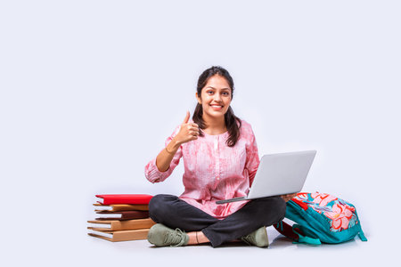 Indian asian female college student studying while sitting on white background with laptop booksの写真素材