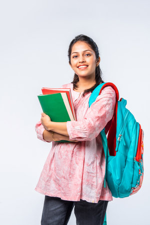 Indian asian young college girl with backpack, laptop, books pointing or ok signの写真素材