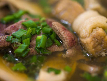 Asian dish of a herbal, tea flavored soup of pork ribs, liver and stomach, garnished with chopped spring onions, served steaming hotの写真素材