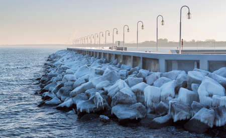 Ice covered stones in the sea near the pierの写真素材