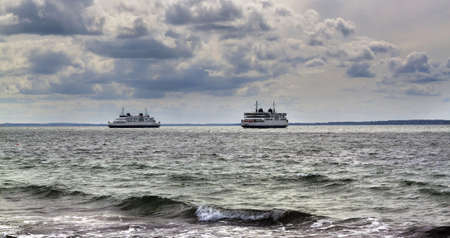 Two ferry are going from the opposite directions in cloudy dayの写真素材