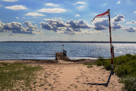 Small wooden pier from beach to sea with city on the horizonの写真素材
