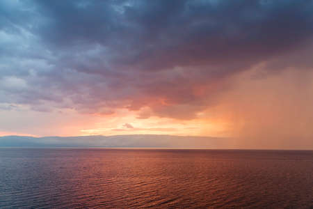Rain storms are happening at sea on sunset skyの写真素材