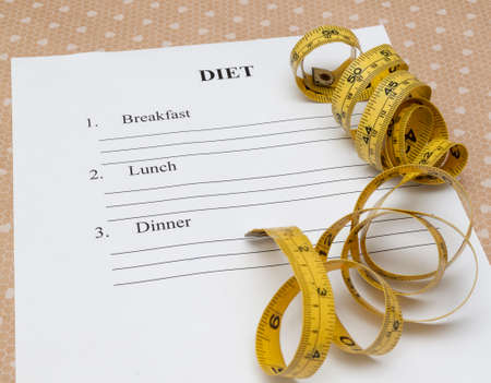 paper with diet plan and roll yellow measure tape on yableの写真素材
