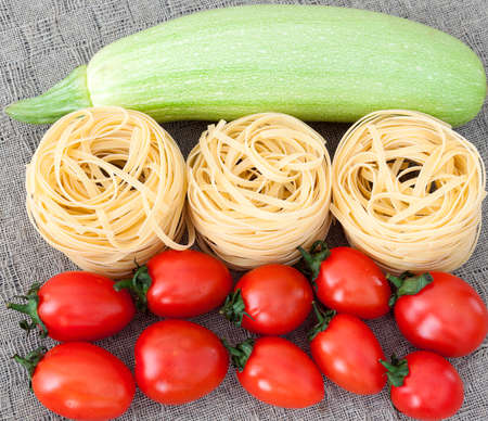 raw uncooked pasta and vegetables on gray linen backgroundの写真素材