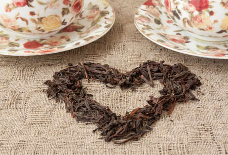 Two cups of tea and heart made by lives on the table. Tablecloth is linenの写真素材