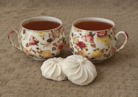 two half of marshmallows and two cups of teaの写真素材