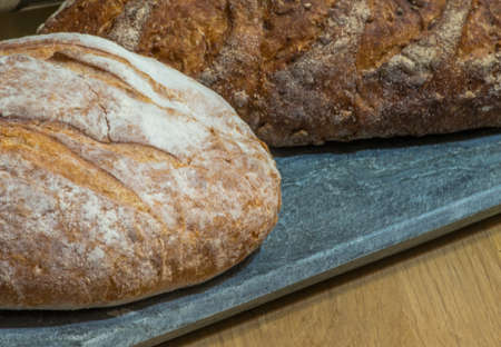 Crusty Handmade Bread on Marble Chopping Board and Wooden Table
