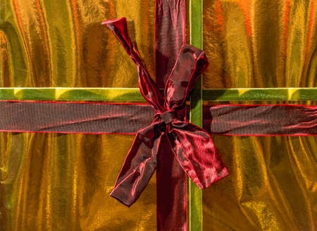 Present Wrapped up in Gold Paper with Deep Red Bowの写真素材