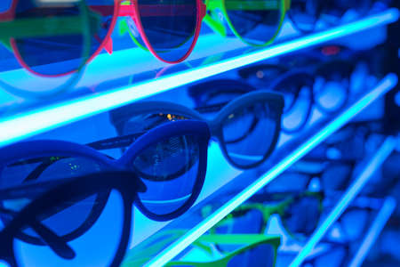 Stylish Sunglasses on Blue Neon Shelf in Shop