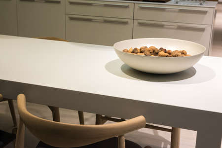 Minimalist Kitchen with Clean Surfaces and Bowl of Nuts on Table and Wooden Chair