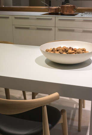 Minimalist Kitchen with Clean Surfaces and Bowl of Nuts on Table and Wooden Chair