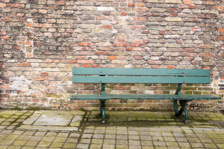 Traditional Green Bench Seat with Old Brick Wall in Backgroundの写真素材