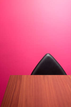 Bright Pink Office Space with Large Wooden Desk and Artistic Angular Black Leather Chair